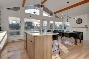 Una cucina moderna con isola centrale, ampie finestre e zona pranzo con tavolo e sedie.