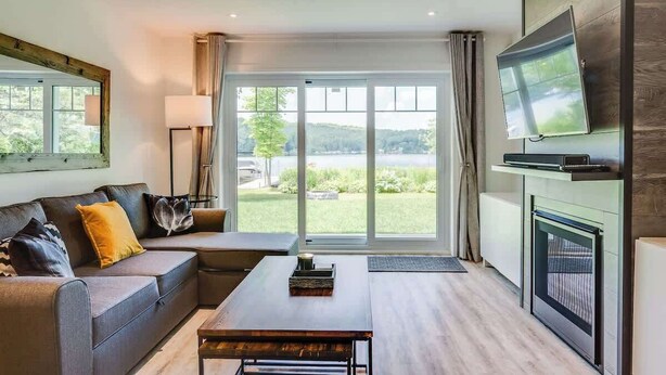 Ein modernes Wohnzimmer mit einer Couch, einem Couchtisch und einem an der Wand montierten Flachbildfernseher.