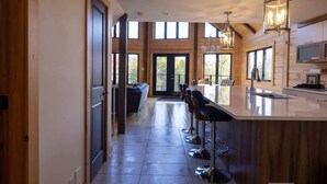 A modern kitchen with a large island, bar stools, and pendant lighting.