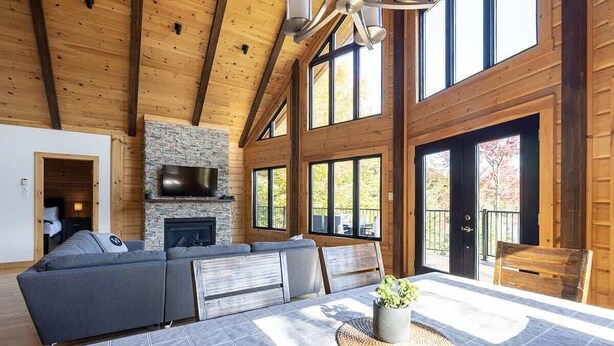 A spacious living room with a large sectional sofa, a stone fireplace, and a dining table with a woven placemat.