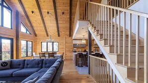 A spacious living area with a large sectional sofa, a dining table, and a kitchen in the background.