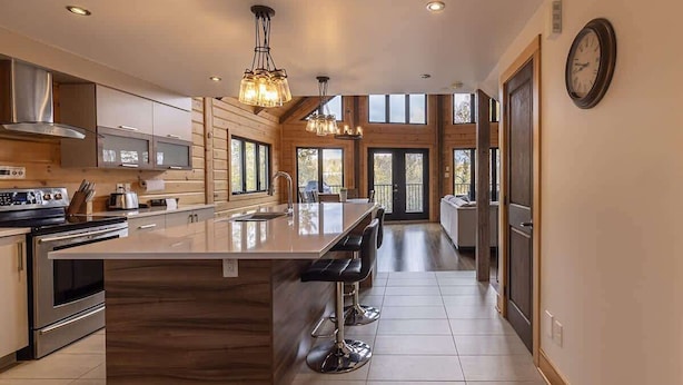 Una cocina moderna con una isla grande, electrodomésticos de acero inoxidable y paneles de madera.