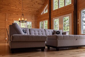 A wooden interior with a sectional sofa and large windows.