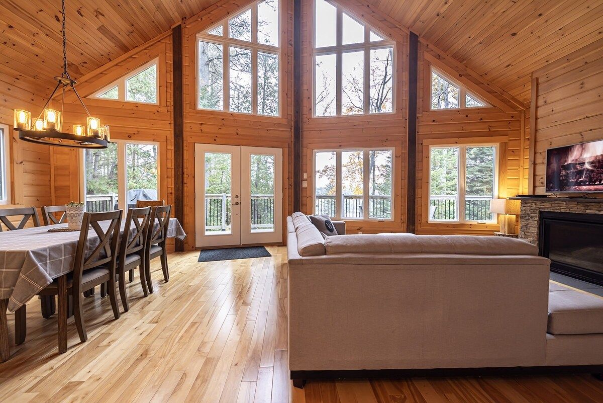 A log cabin interior with a dining area, a sofa, and a fireplace.