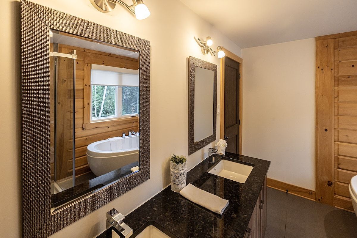 A bathroom with a large mirror, a sink, and a window.