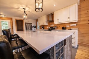 A modern kitchen with white cabinets, a large island, and black bar stools.