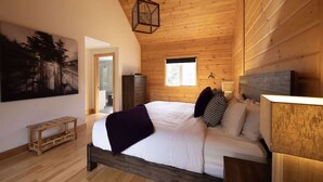 A wooden-paneled bedroom with a large bed, a hanging light fixture, and a painting on the wall.