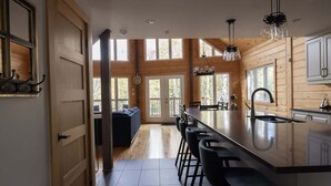 A modern kitchen with a large island, bar stools, and wooden cabinetry.