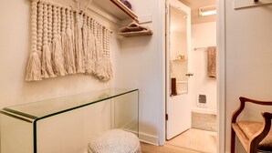 Un pasillo con un banco de vidrio, un colgador de macramé y una silla de madera.
