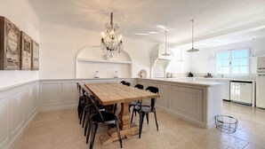 A spacious kitchen with a wooden dining table, white cabinetry, and a chandelier. - Charming villa with garden and heated pool, perfect families (Saint Paul de Vence)