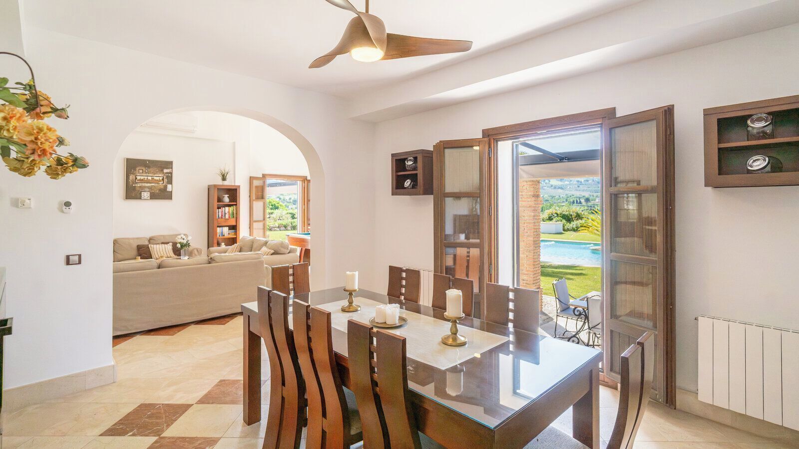 Un comedor con mesa, sillas y vista a una piscina.