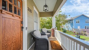 A porch with wicker furniture, a wooden door, and a mailbox.