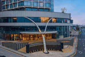 A modern building with a curved facade, large glass windows, and a prominent entrance with a metal archway. - Like Hotel (Guiyang)