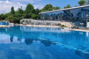 A swimming pool with a clear blue water surface, surrounded by a modern building with large windows, and a staircase leading to an upper level. - Like Hotel (Guiyang)