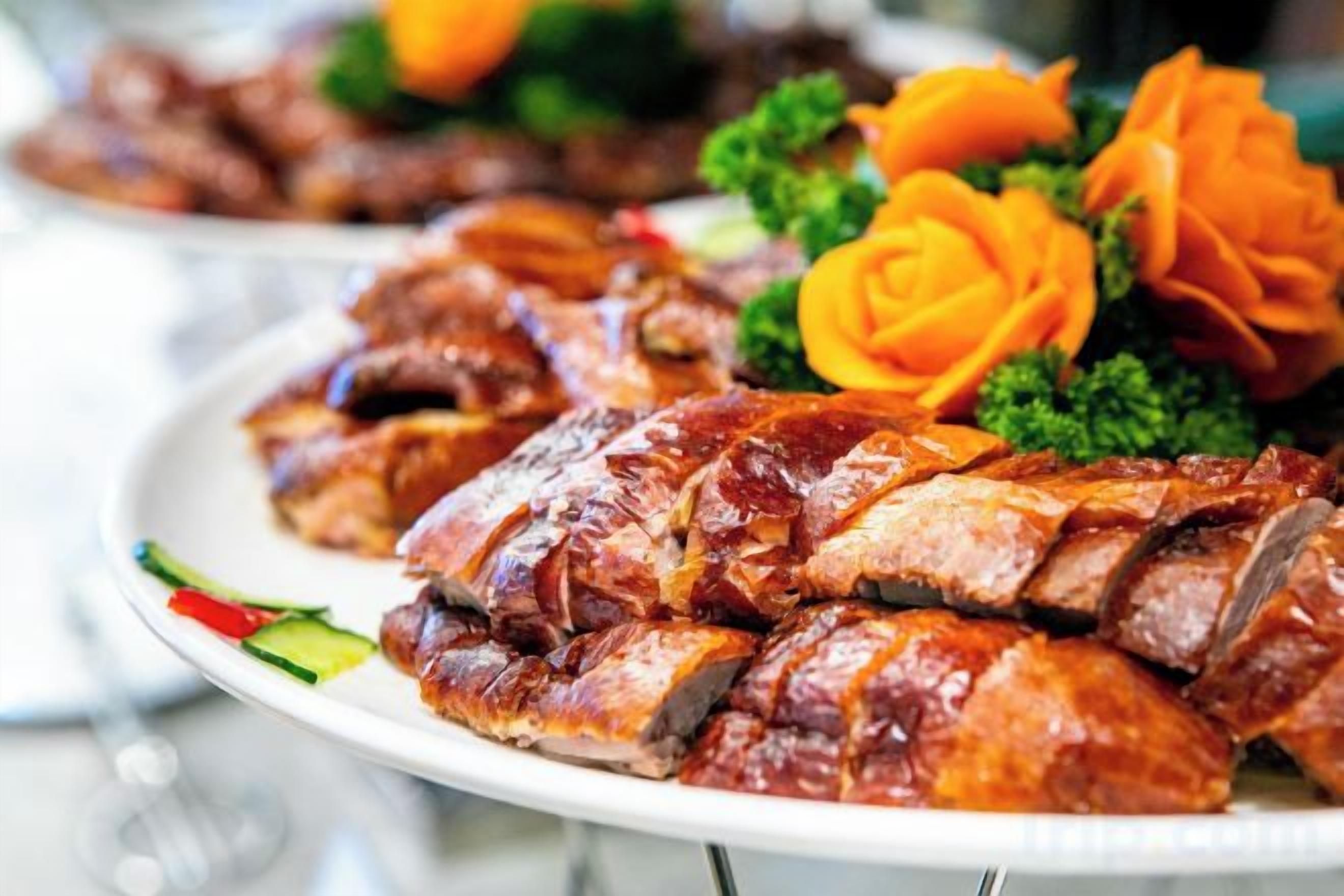 A plate of sliced roasted meat garnished with vegetables.