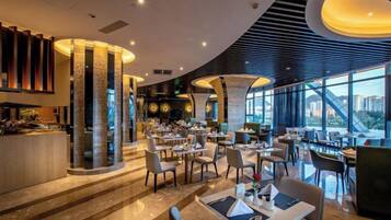 Un restaurant moderne doté d’un bar, de différents types de tables et de grandes fenêtres offrant une vue panoramique.