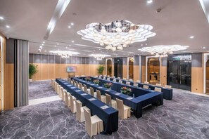 Une salle de conférence avec une longue table, des chaises et un lustre moderne.