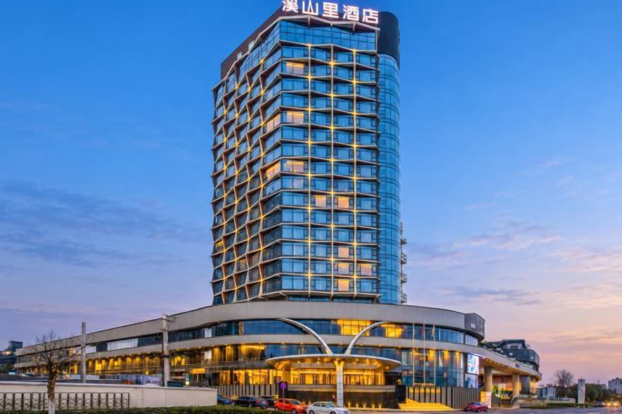 Ein Hochhaus-Hotel mit modernem Design, das eine markante, geschwungene Eingangshalle und eine große Glasfassade zeigt.