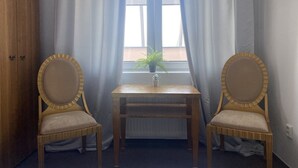 A room with two wooden chairs, a small table, and a window with curtains.