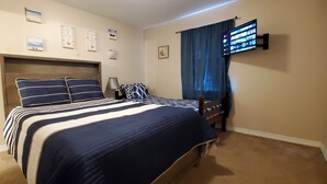Una camera da letto con un letto, una TV a parete e un comodino.
