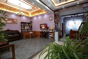 A living room with a sofa, coffee table, and chairs, a bookshelf, and a dining area with a table and chairs. - Biancheng Shanshui Inn (Fenghuang County)