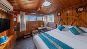 Une pièce de cabane en bois comprenant un lit, une télévision, une fenêtre et une petite table.