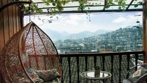 Un balcon avec un fauteuil suspendu, une petite table et des chaises avec des coussins.