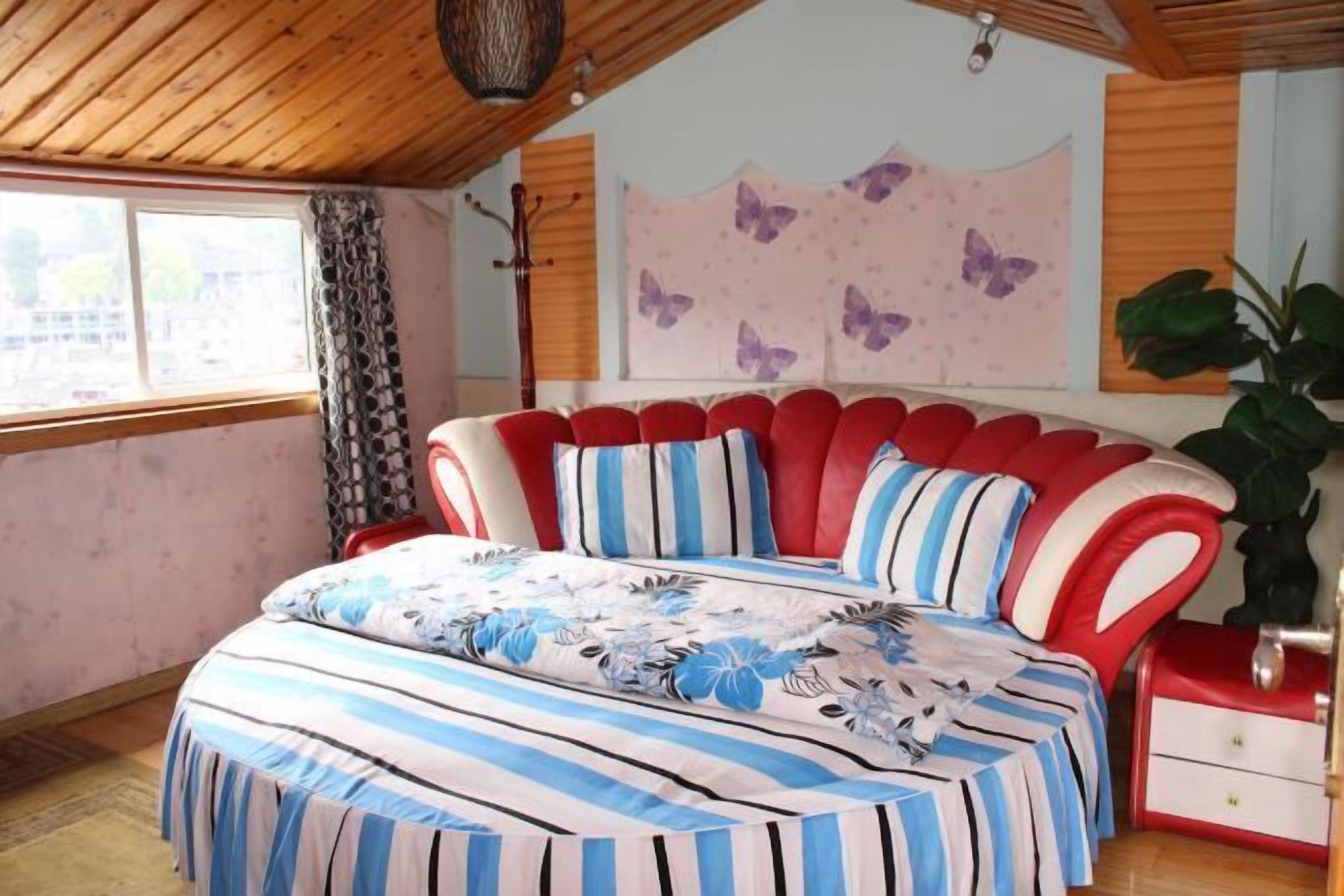 Une chambre à coucher dotée d’un lit au design incurvé original, d’une fenêtre ornée de rideaux à motifs et d’un mur décoré de motifs de papillons.