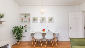 Un comedor con una mesa blanca, dos sillas y una lámpara colgante.