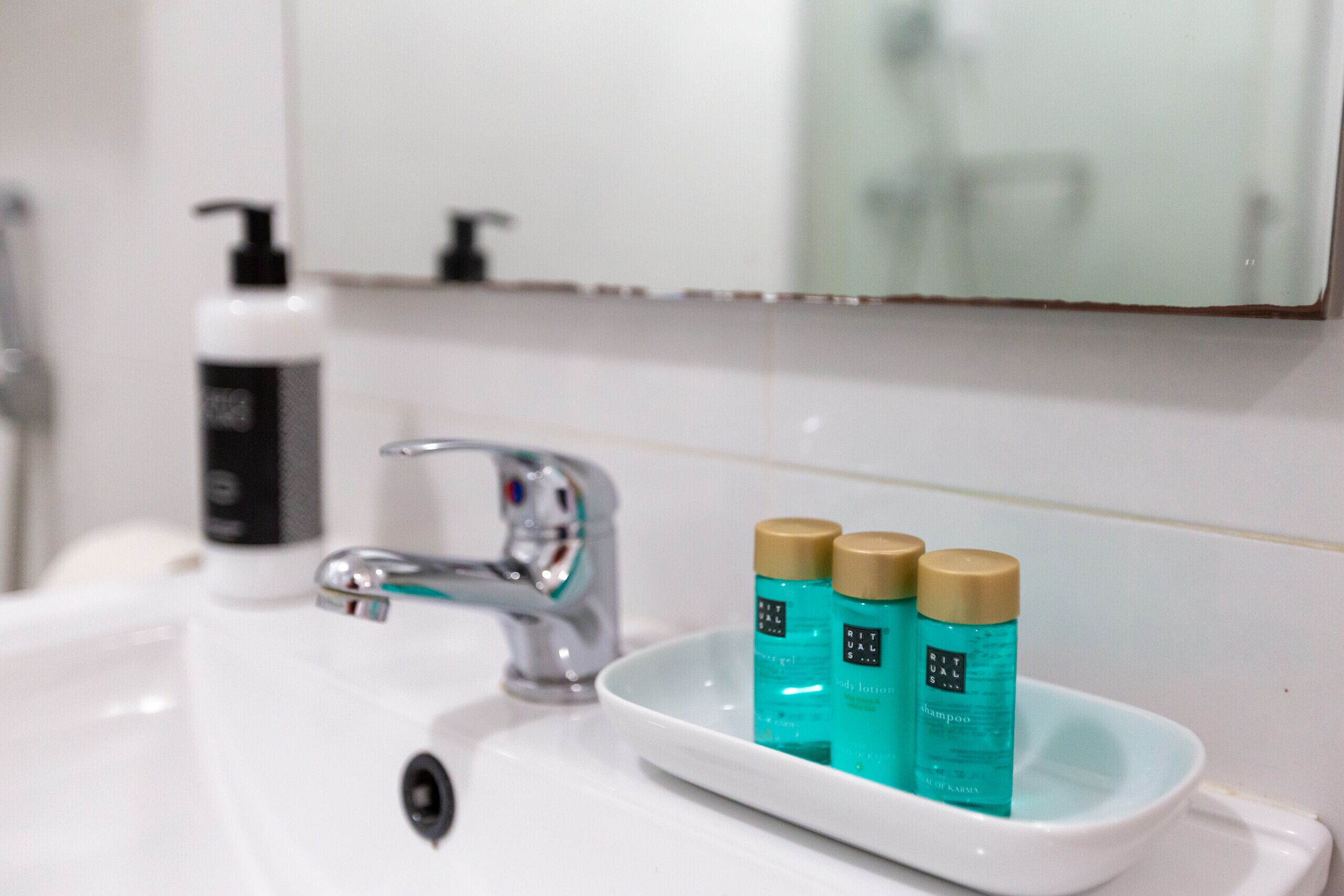 A bathroom sink with a chrome faucet and two bottles of body lotion on the edge.