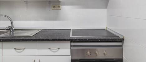 A modern kitchen with white cabinets, a stainless steel stove, and an oven.