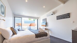 Ein modernes Schlafzimmer mit einem großen Bett, einem Schreibtisch und Blick ins Freie.
