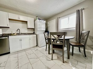 A kitchen with white cabinets, a white refrigerator, a stove, and a dining table with chairs. - 285 Whitaker unit B NEW · A Great Place for Workers on Whitaker (Hamilton)