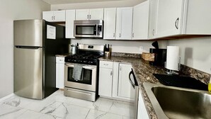 Una cocina con armarios blancos, electrodomésticos de acero inoxidable, encimera de granito y un fregadero.