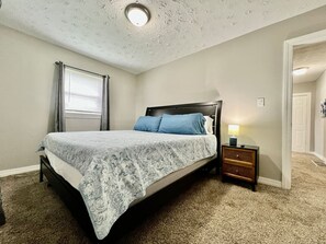A bedroom with a bed, a nightstand, a window with curtains, and a door. - 285 Whitaker unit B NEW · A Great Place for Workers on Whitaker (Hamilton)
