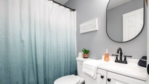 A bathroom with a toilet, sink, and a shower curtain.