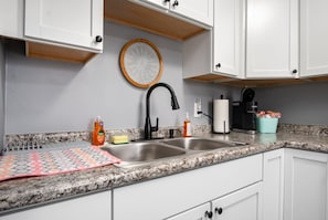 A kitchen with white cabinets, a granite countertop, a black faucet, and a coffee machine. - 17 S First - Unit 6 · 17 s first street unit 6 (Trenton)