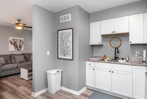A modern kitchen with white cabinets, a granite countertop, and a ceiling fan. - 17 S First - Unit 6 · 17 s first street unit 6 (Trenton)