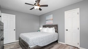 A bedroom with a bed, a ceiling fan, and two white doors.