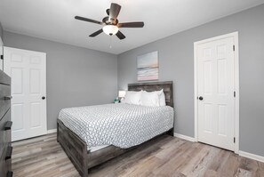 A bedroom with a bed, a ceiling fan, and two white doors.