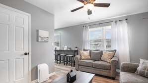 A living room with a grey sofa, a wooden coffee table, and a ceiling fan.