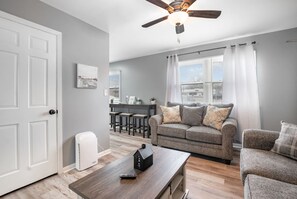 A living room with a grey sofa, a wooden coffee table, and a ceiling fan.