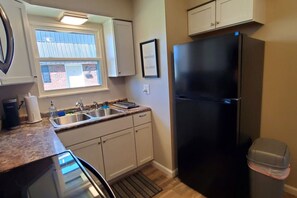 A kitchen with a black refrigerator, a sink, and cabinets.