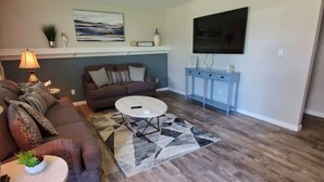 A living room with a brown sofa, a round coffee table, and a patterned rug.