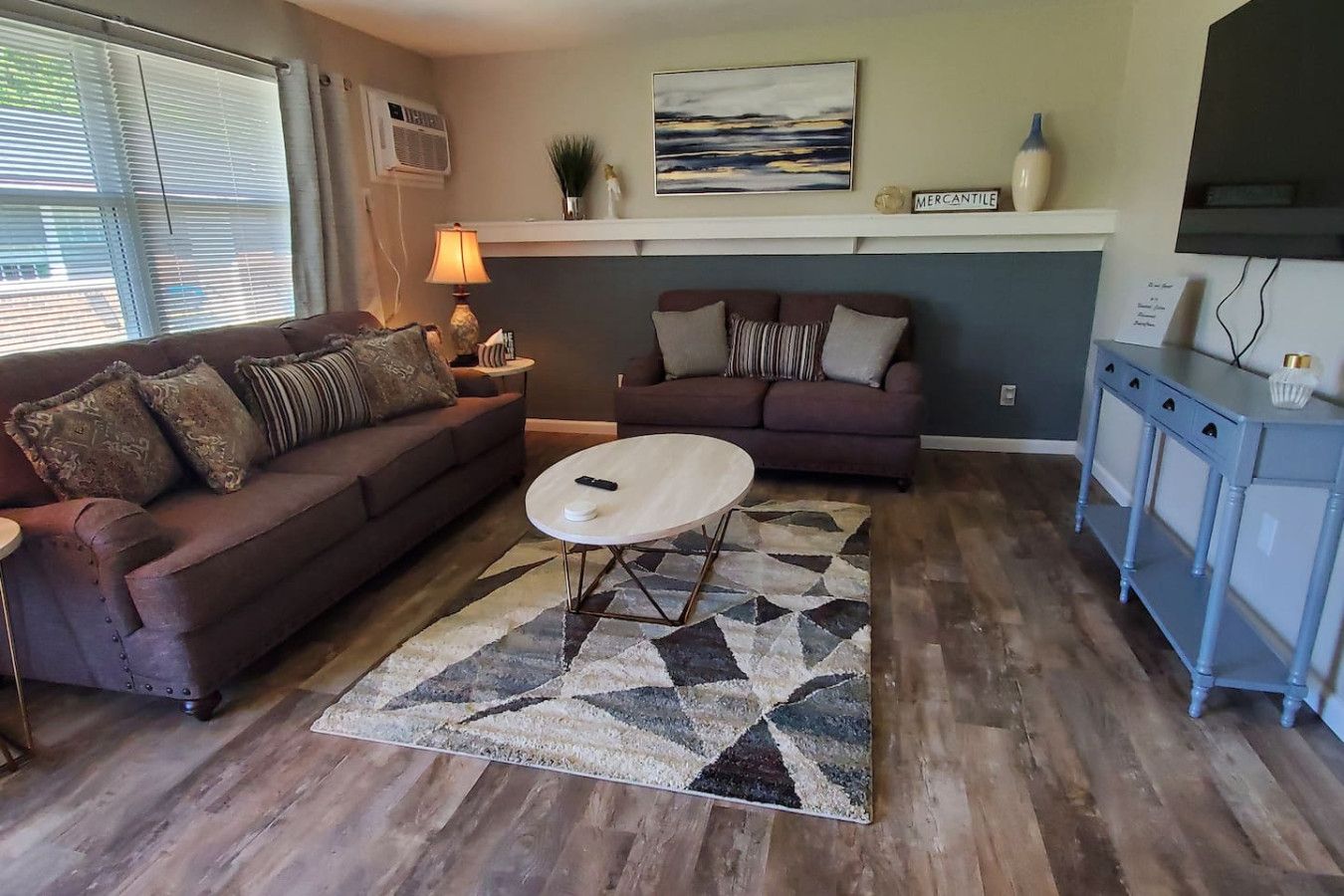 A living room with two sofas, a coffee table, a rug, and a cabinet.