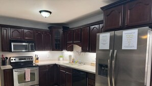 Una cocina con armarios de madera oscura, electrodomésticos de acero inoxidable y un refrigerador con un mensaje.