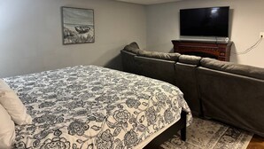 Un dormitorio con cama, sofá, televisor y chimenea.