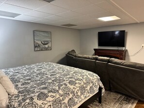 Een slaapkamer met een bed, een bank, een televisie en een open haard.