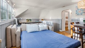 A compact bedroom with a large bed, a desk, and a dining area.