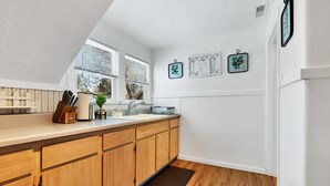 A kitchen with wooden cabinets, a sink, and a window with blinds.